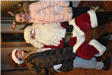 Two Girls Wearing Antlers Smile for a Photo with Santa