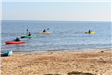 People Paddling Kayaks off the Beach Shore