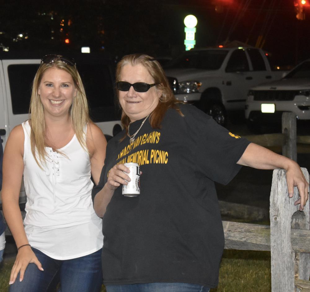Two Women Standing Beside a Wood Fence